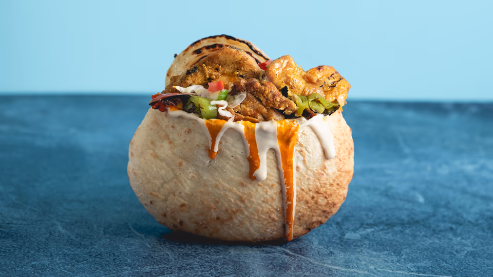 Brown of the chicken (pargit) served in a pita with onion and other veg
